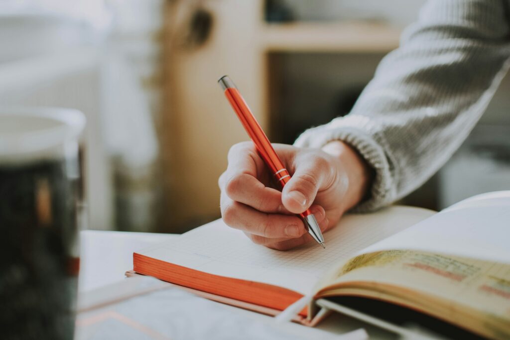 lilartsy-333oj7zFsdg-unsplash someone writing on a notebook
