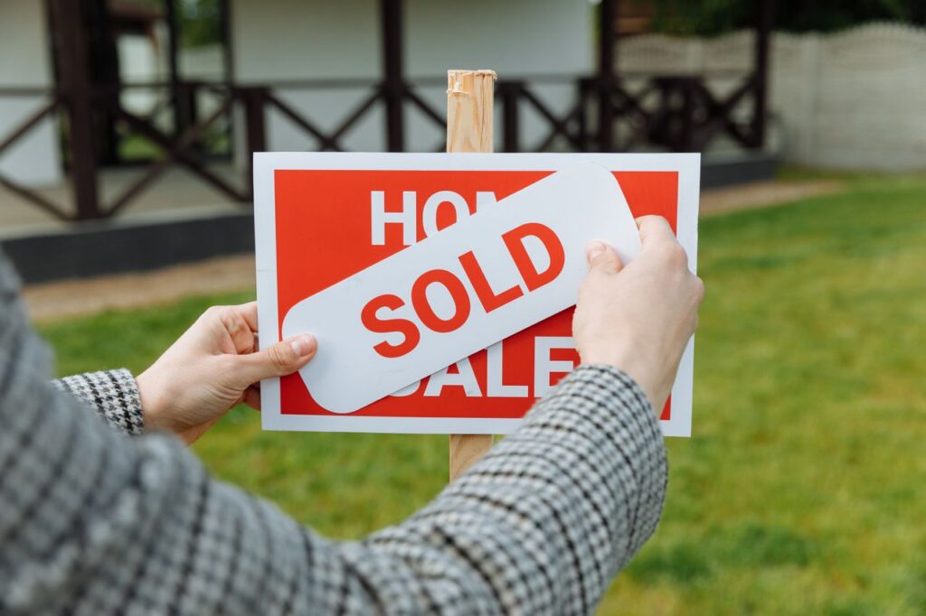 realtor posting a "sold" sticker on signage