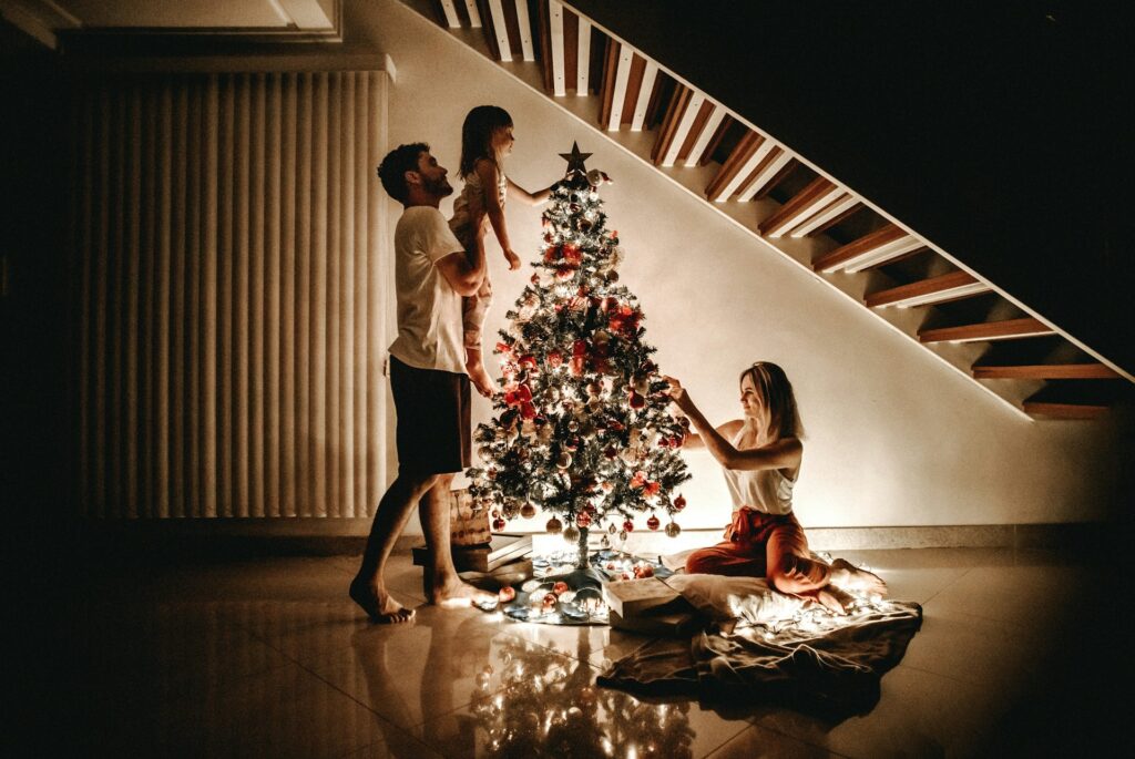jonathan-borba-vcX5AhBwk6s-unsplash family decorating a Christmas tree