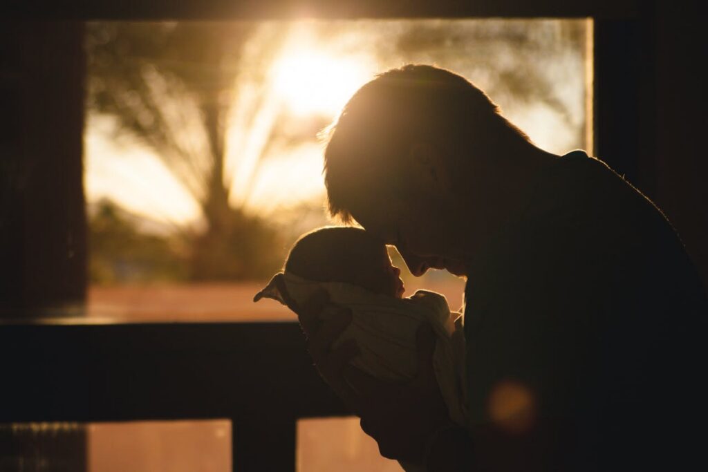silhouette of a man carrying a baby