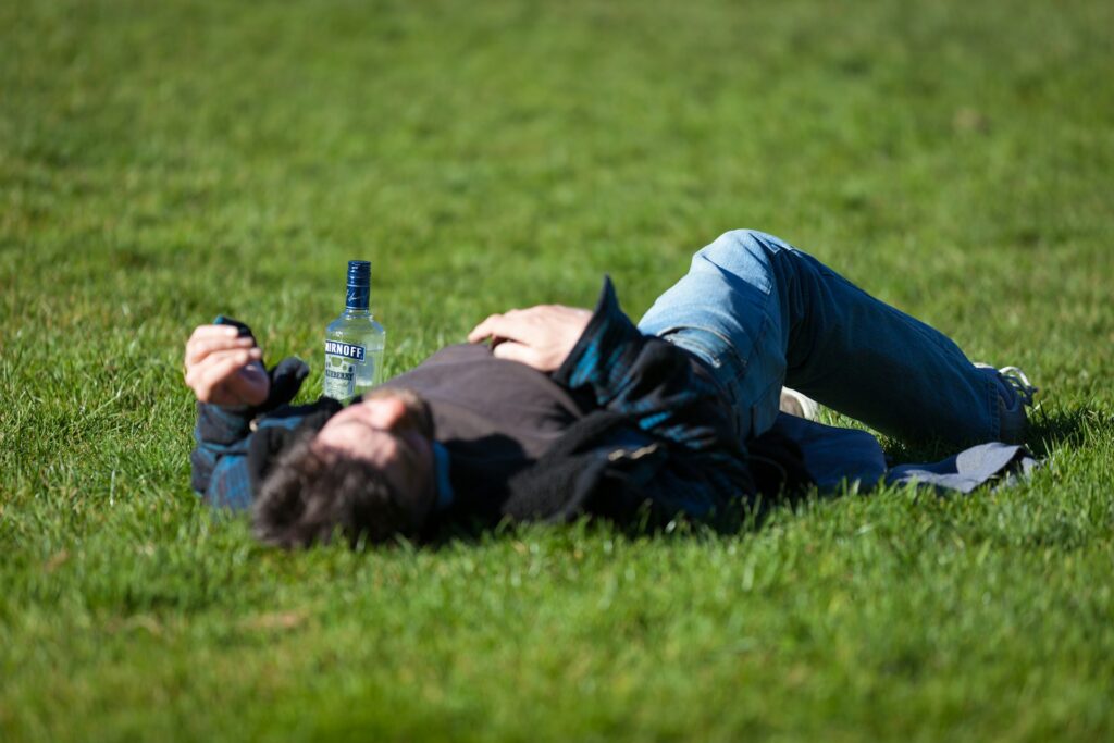 thom-masat-fOKaK7EjydM-unsplash man lying on the grass with beer bottle