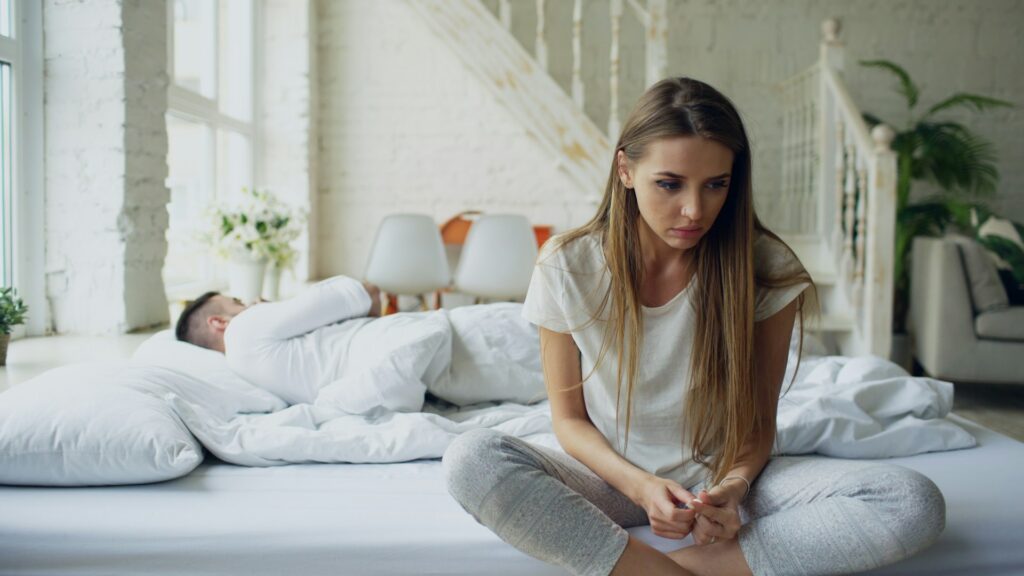 vitaly-gariev-TRrEeqaLm2o-unsplash woman sitting on a bed, man sleeping beside her