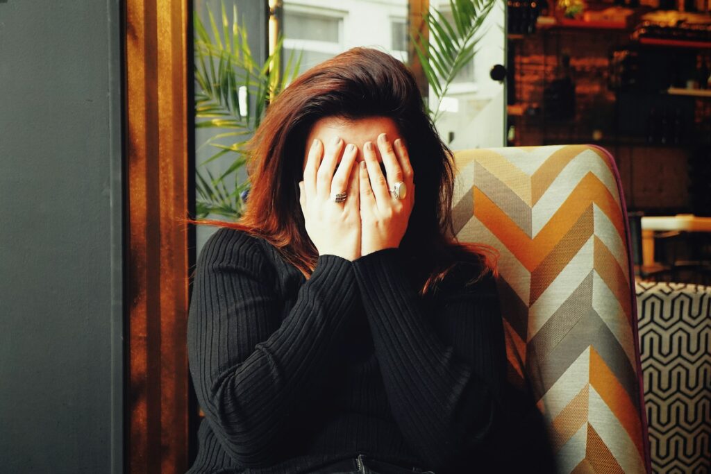 ivan-aleksic-hko-iWhYdYE-unsplash a woman covering her face with her hands