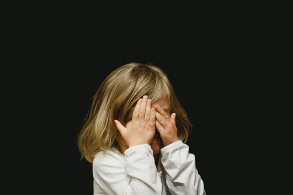 a child covering face with hands