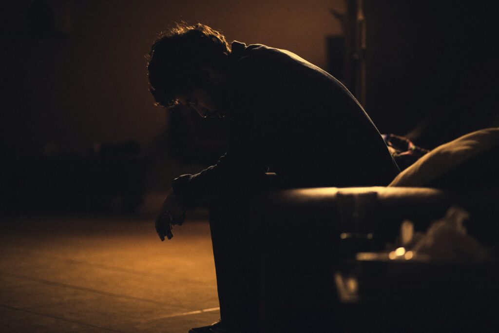 man sitting on a couch, head bowed at  night