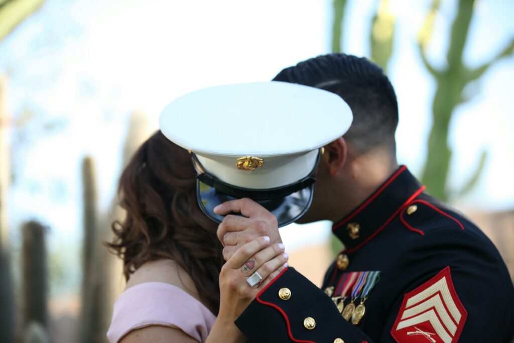uniformed personnel and civilian woman covering face with cap