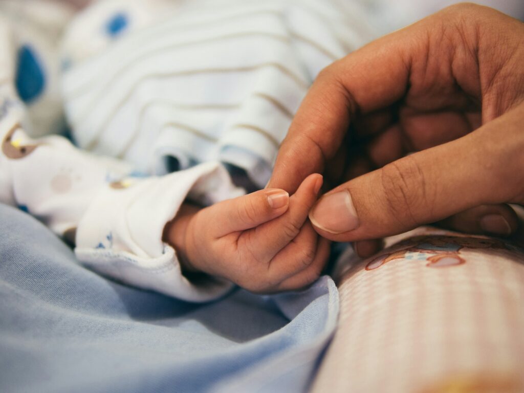 aditya-romansa-5zp0jym2w9M-unsplash adult hand touching a newborn's hand