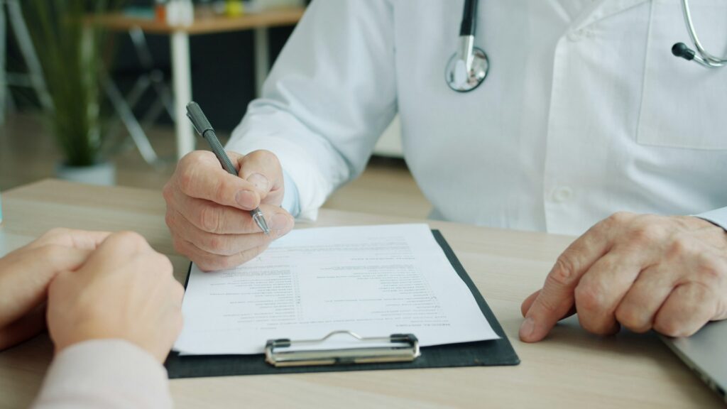 vitaly-gariev-8WYkI3cEZm8-unsplash doctor writing on patient record