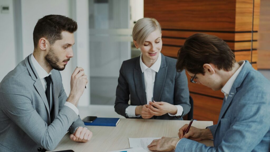 vitaly-gariev-iPheGw7_UaI-unsplash two men and a woman in suit, having ameeting