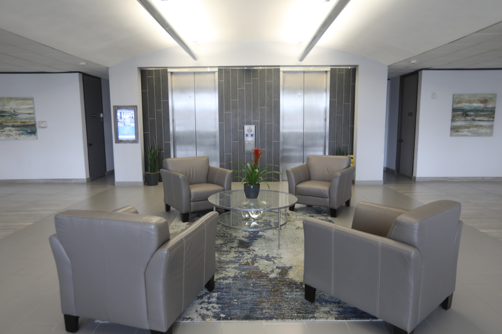 Office lobby seating area with chairs and table near elevators