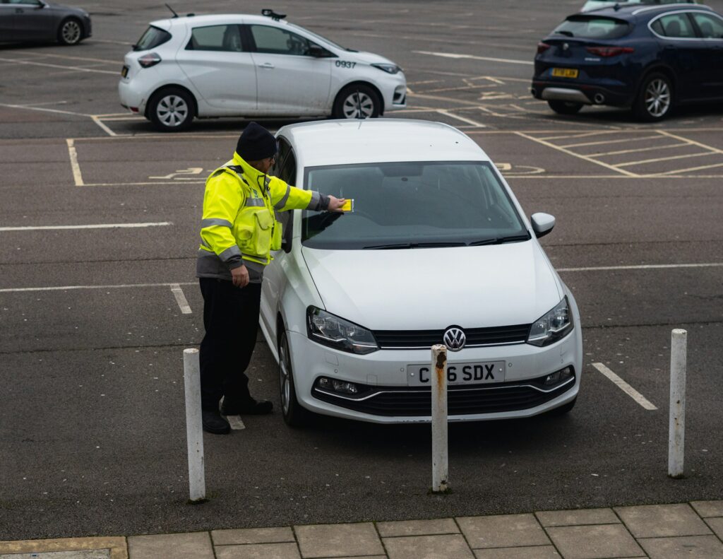 man in yellow jacket standing beside a white car