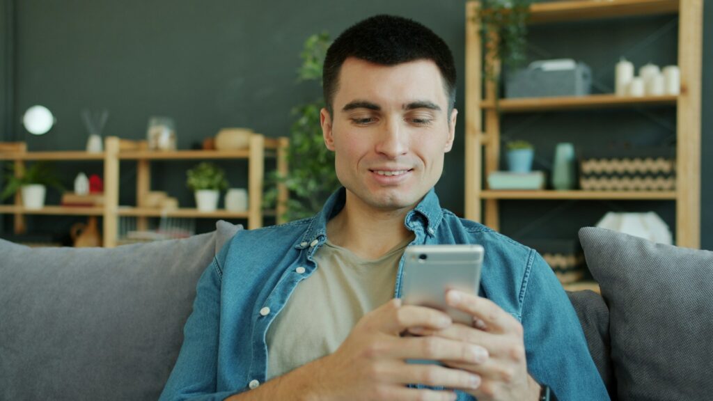 man smiling while using phone