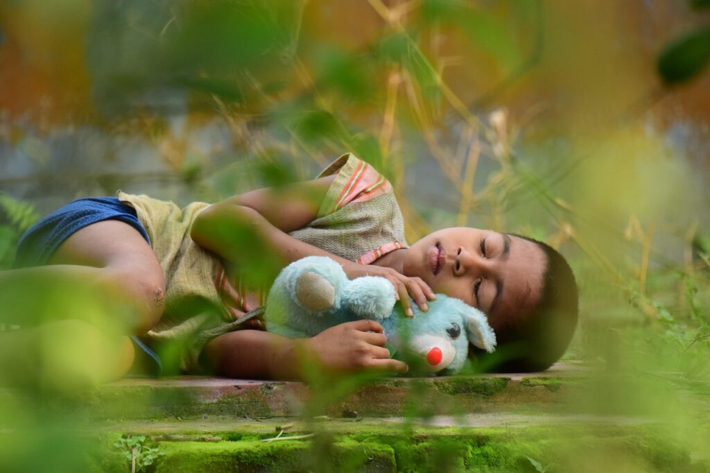 Kid lying on the floor holding a teddy bear