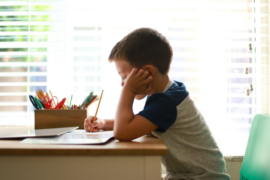 young boy sitting at a desk holding a pencil