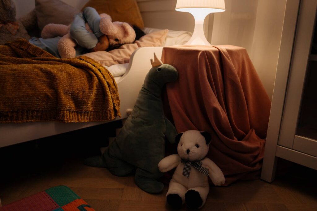 child sleeping on bed, plushies on the floor