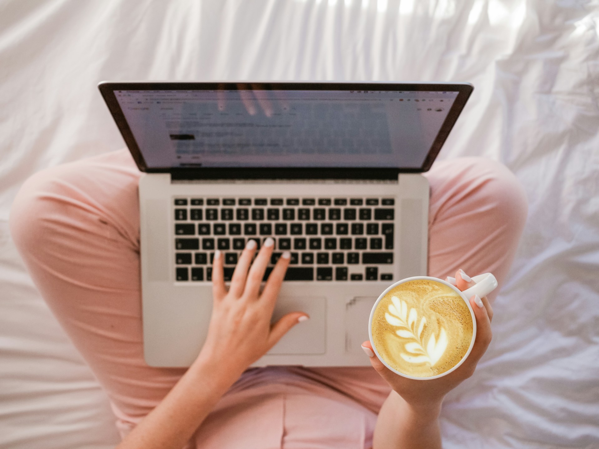 person using laptop while holding cup of coffee