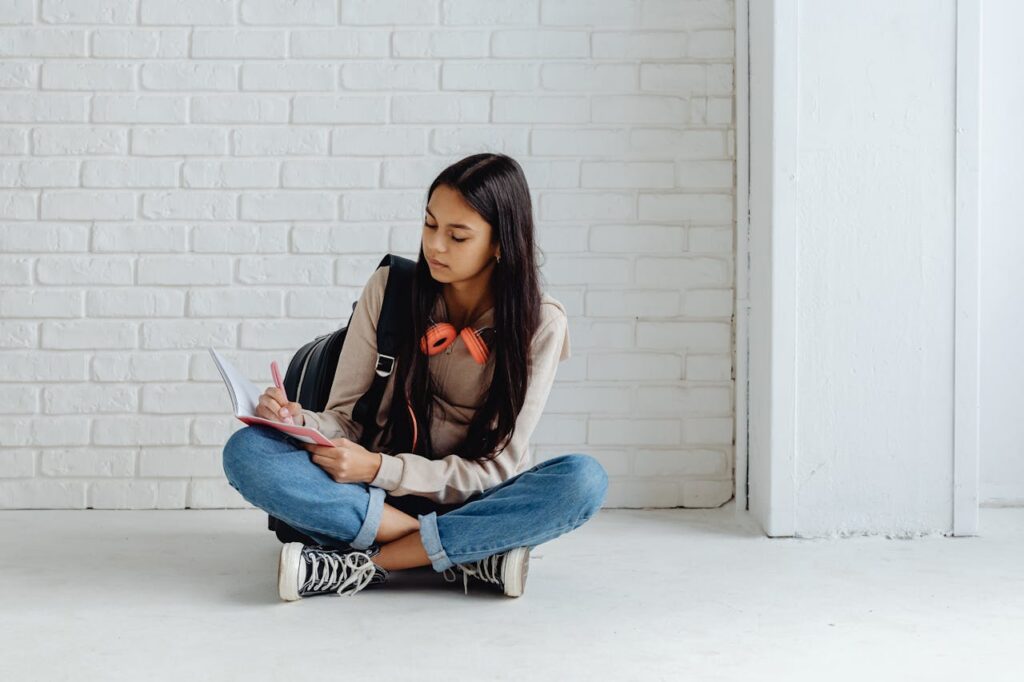 young woman sitting on the floor while writing