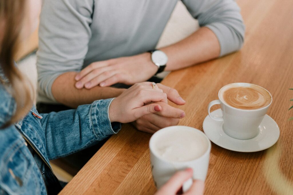 man and woman holding hands, drinking coffee