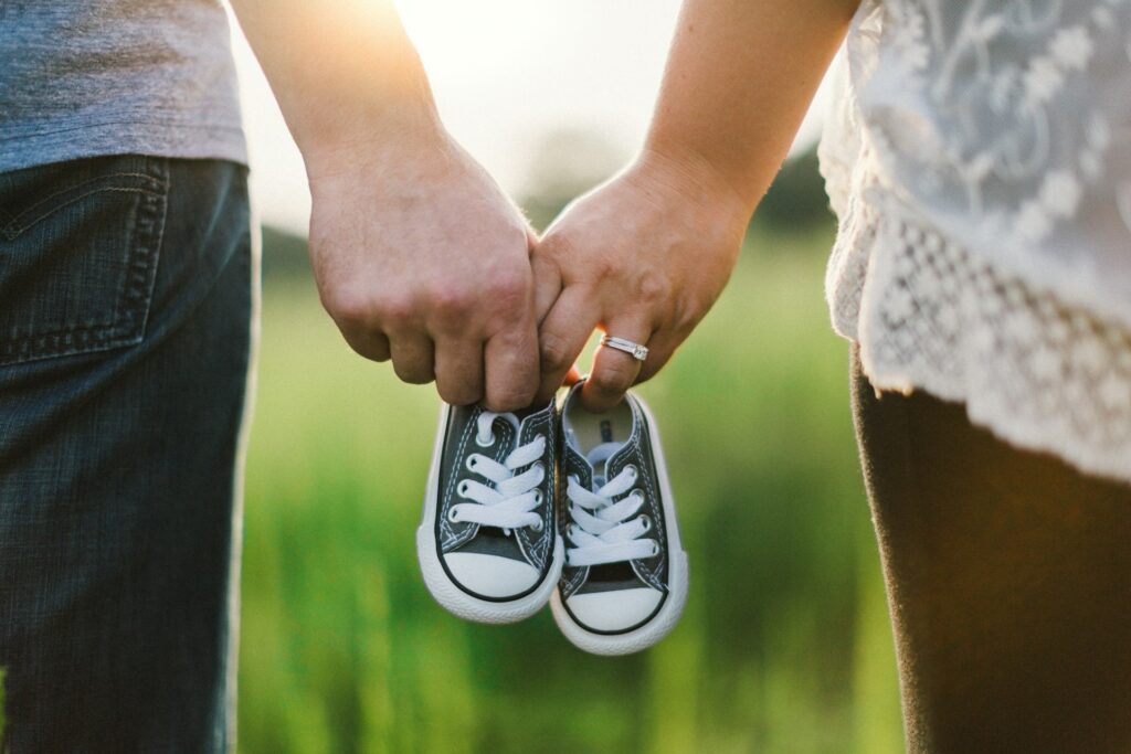 man and woman holding kid shoes