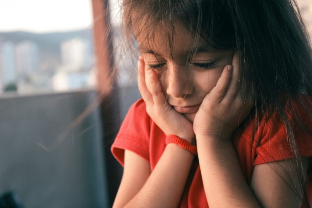 a child holding her face