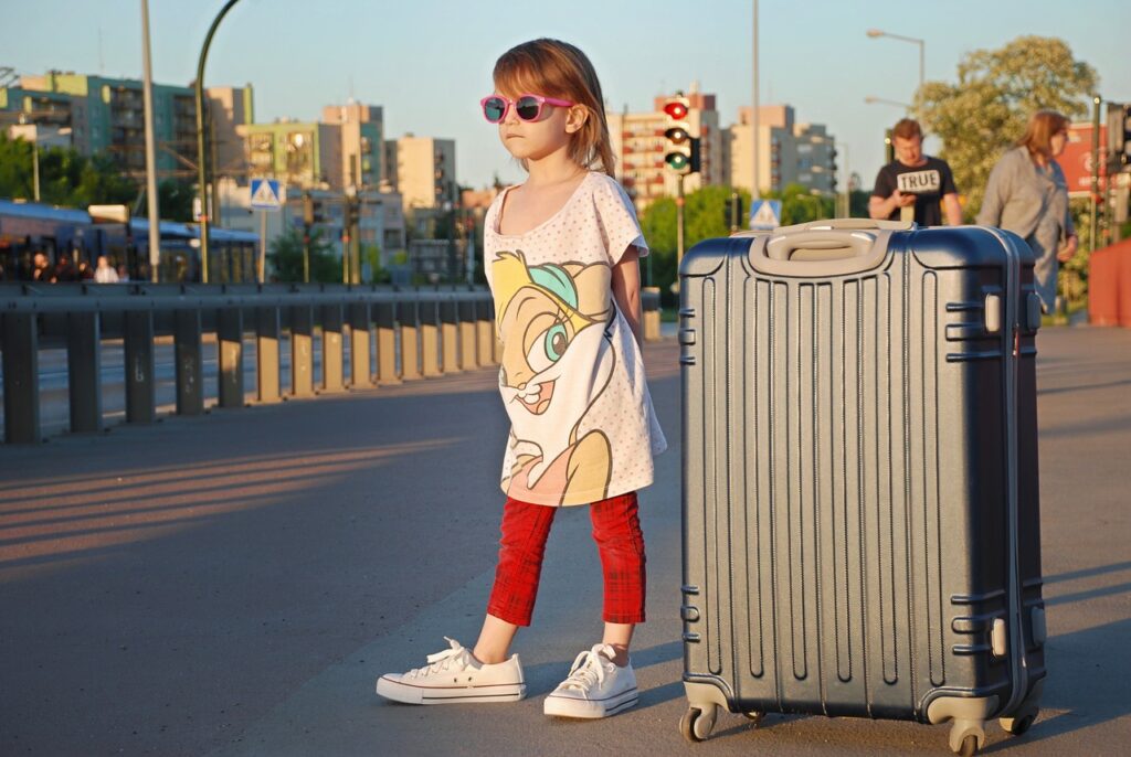 A child with suitcase beside her