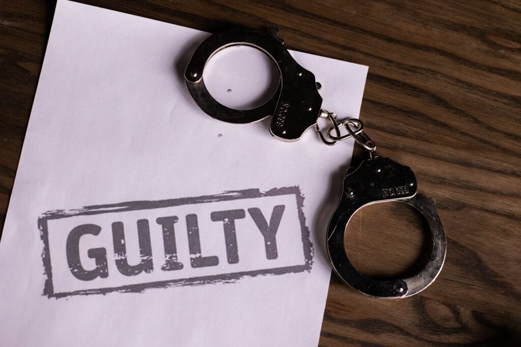 handcuffs and a paper with the word "guilty"