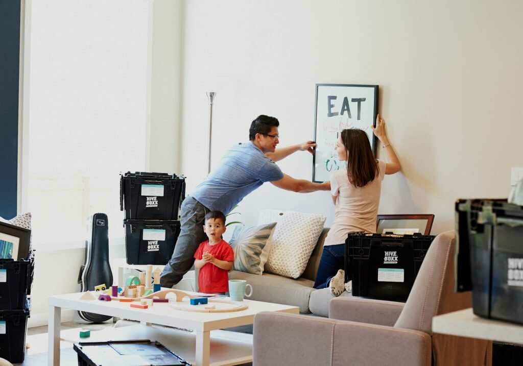 man and woman putting up a frame at home while a child is with them