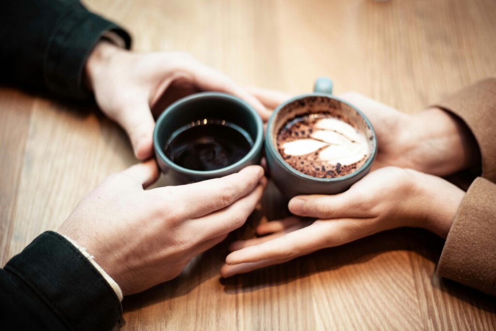 two persons holding mugs with coffee