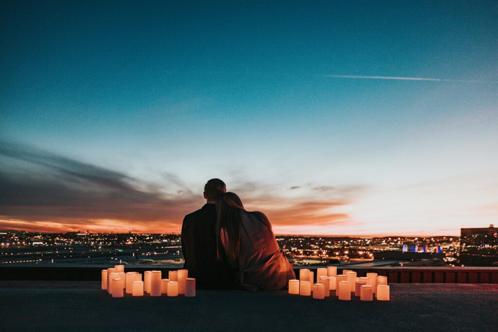 couple sitting on a field surrounded by candles