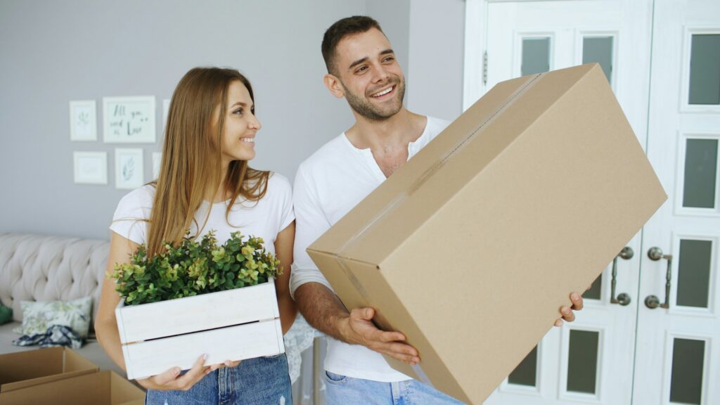 couple carrying large box and plant