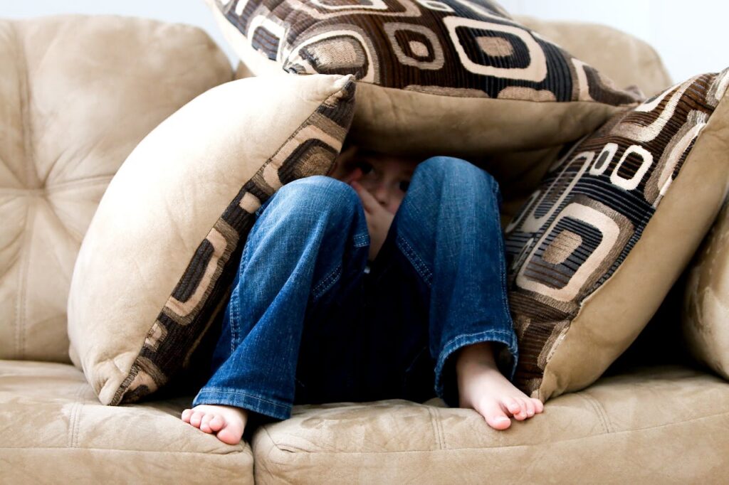 child hiding in sofa cushion
