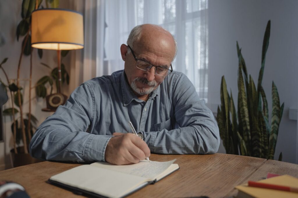 an old man writing on a notebook
