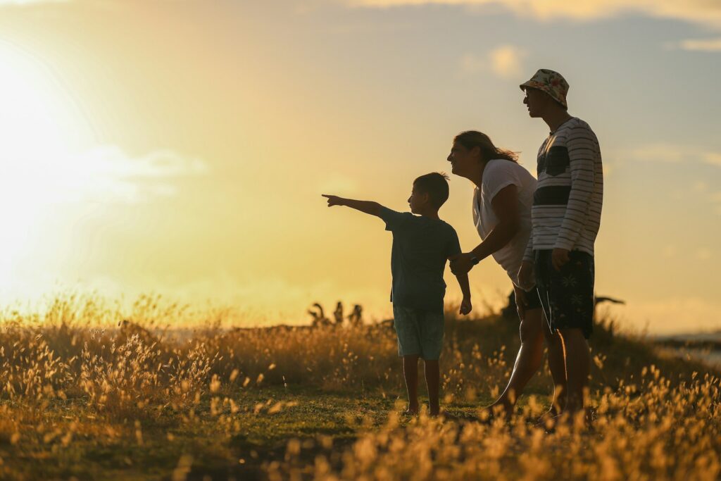 man, woman, and child in a field during sunset