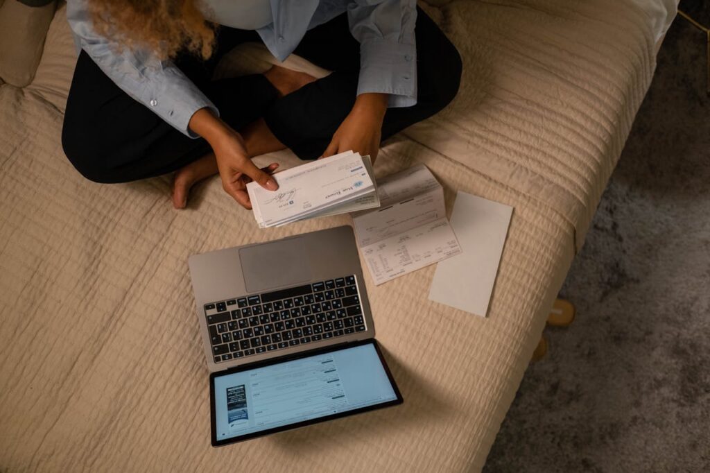 woman holding a cheque in front of a laptop