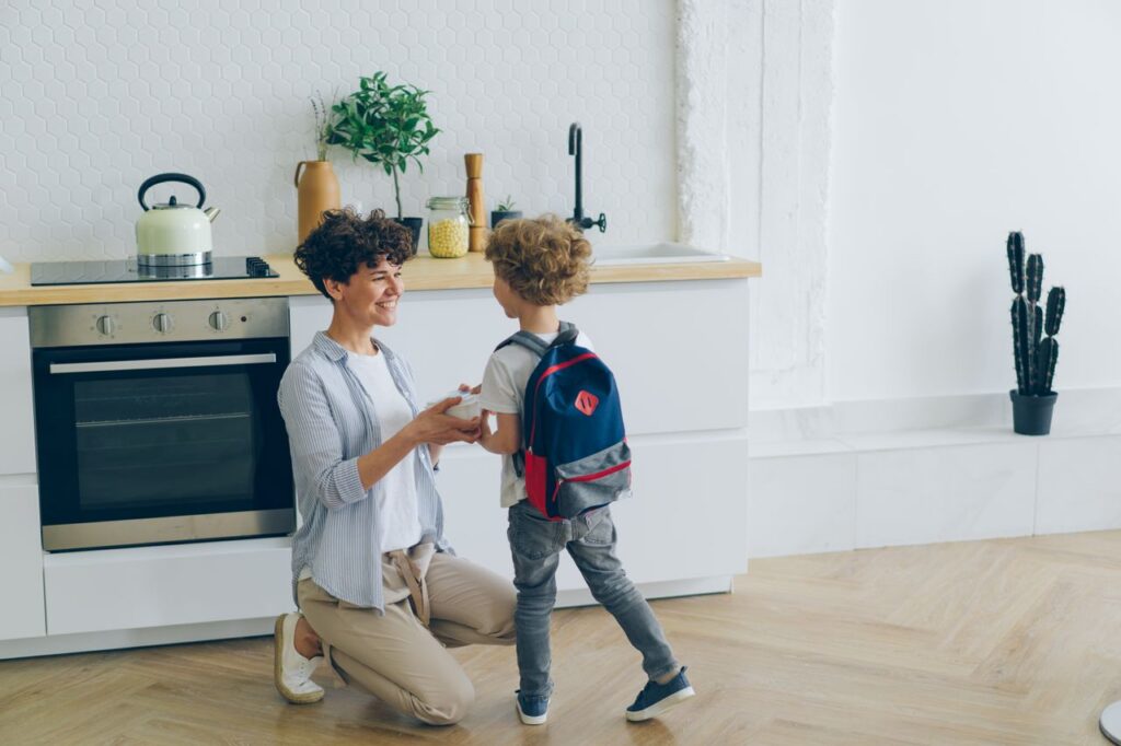 a woman and child wearing backpack in the kitchen