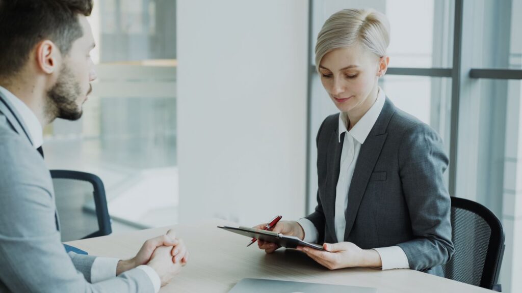 man talking to a woman in business suit and reading from a clipboard