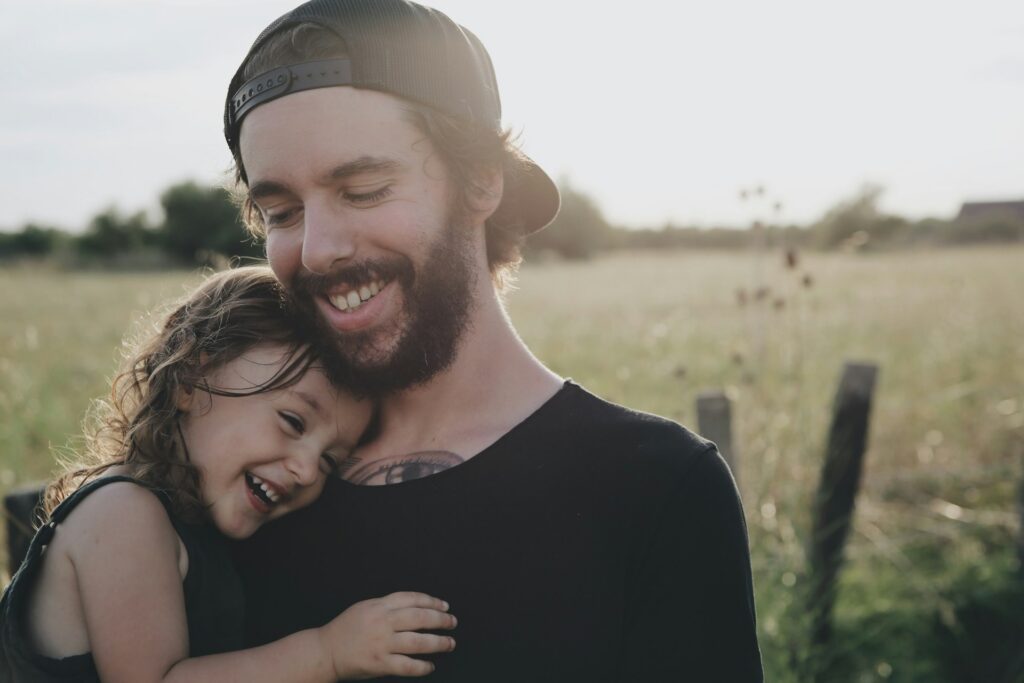 man carrying daughter out on a field