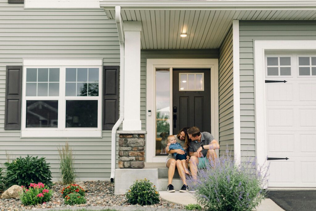 parents with baby in front of house porch