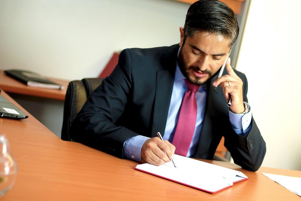 office-2820890_1280 A man in a suit talking on the phone while writing