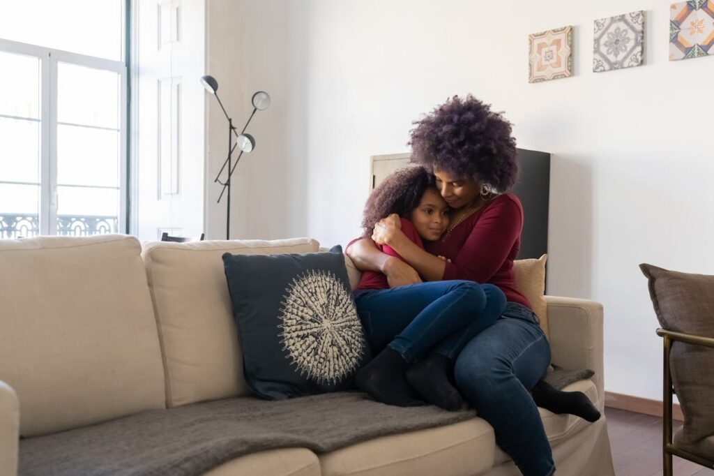 woman sitting in couch, hugging daughter