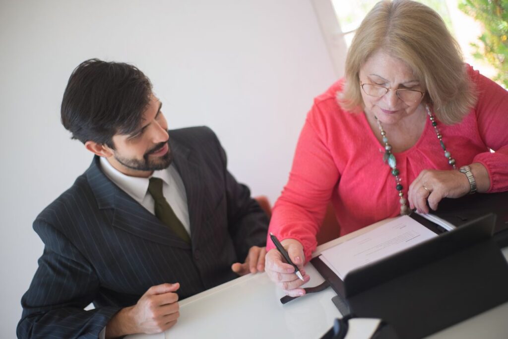 an elderly woman signing a document with a lawyer