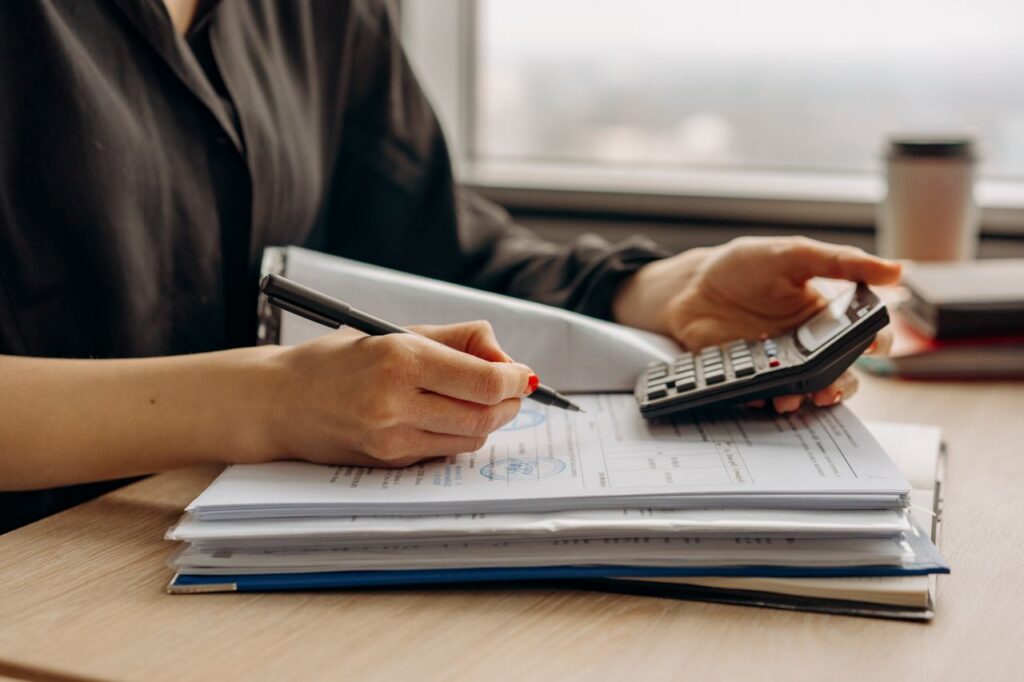 woman using calculator and writing on documents