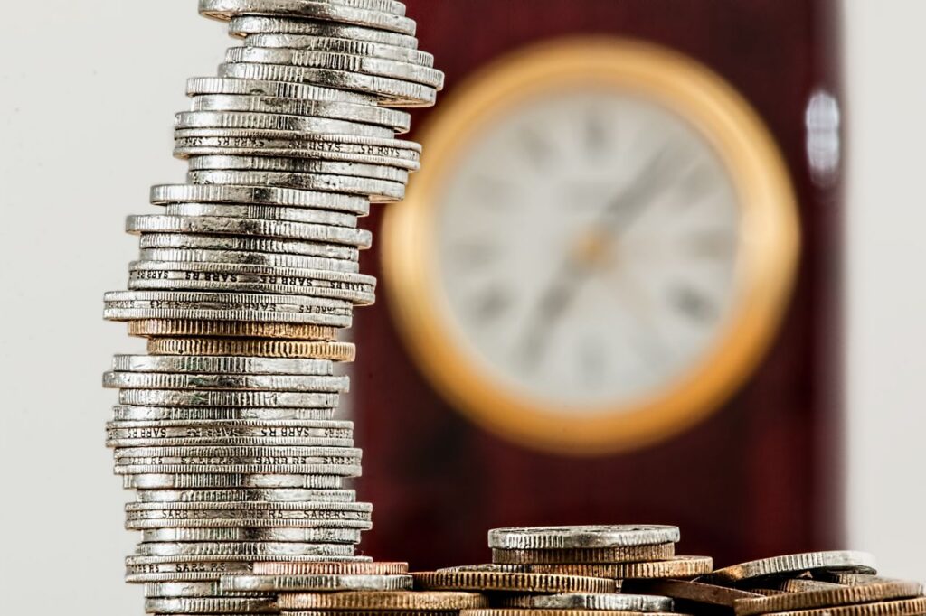 stack of coins and wall clock