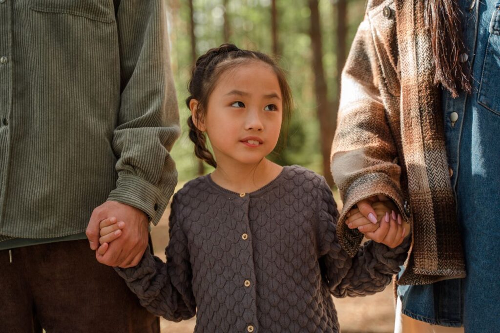 a young girl in between her parents, holding their hands