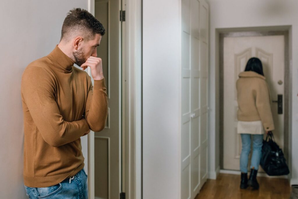 man looking at a woman walking out of an apartment