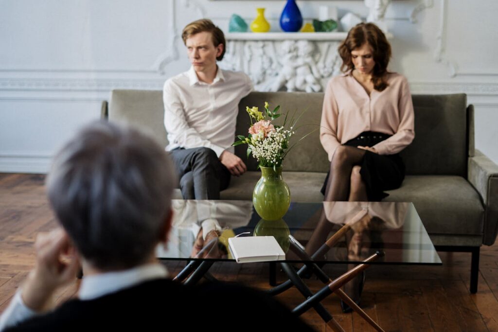 man and woman seated apart facing a counselor