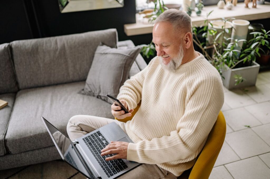 elderly person using a laptop and mobile phone