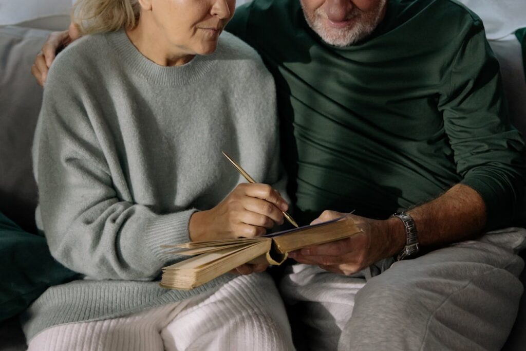 elderly couple writing on paper on top of a book