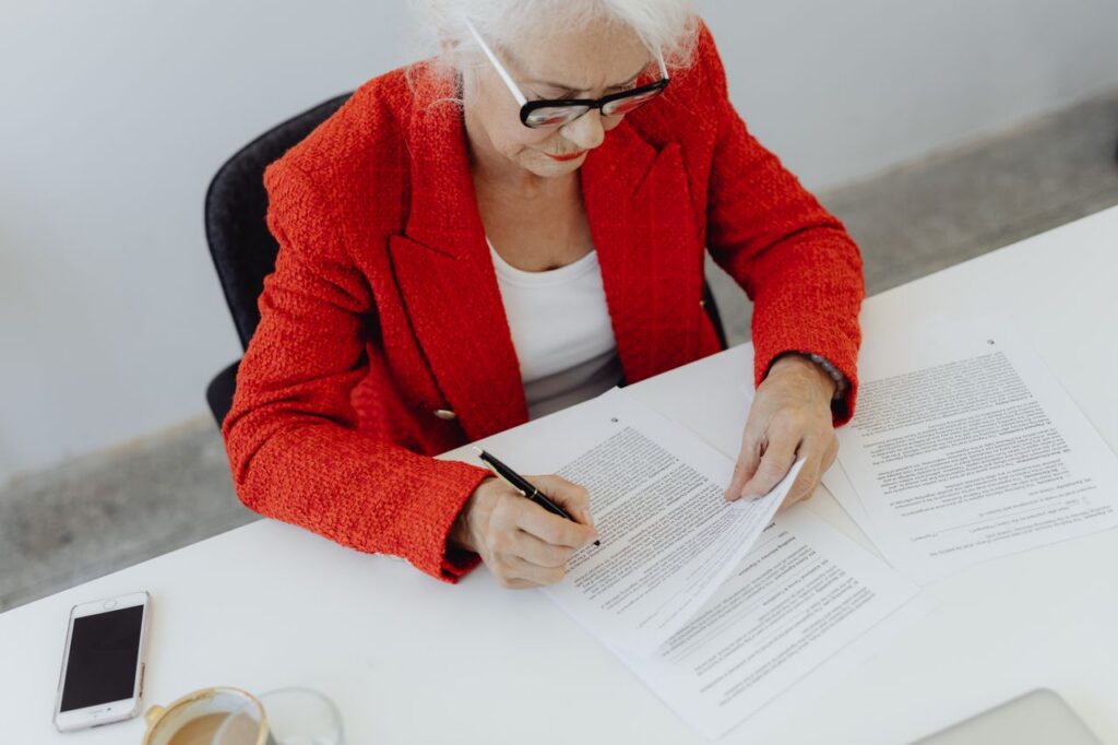 elderly woman signing a document