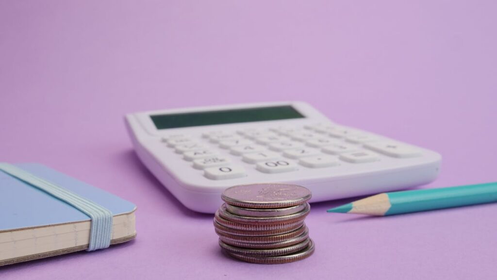 calculator, pencil, notebook and coins on a desk